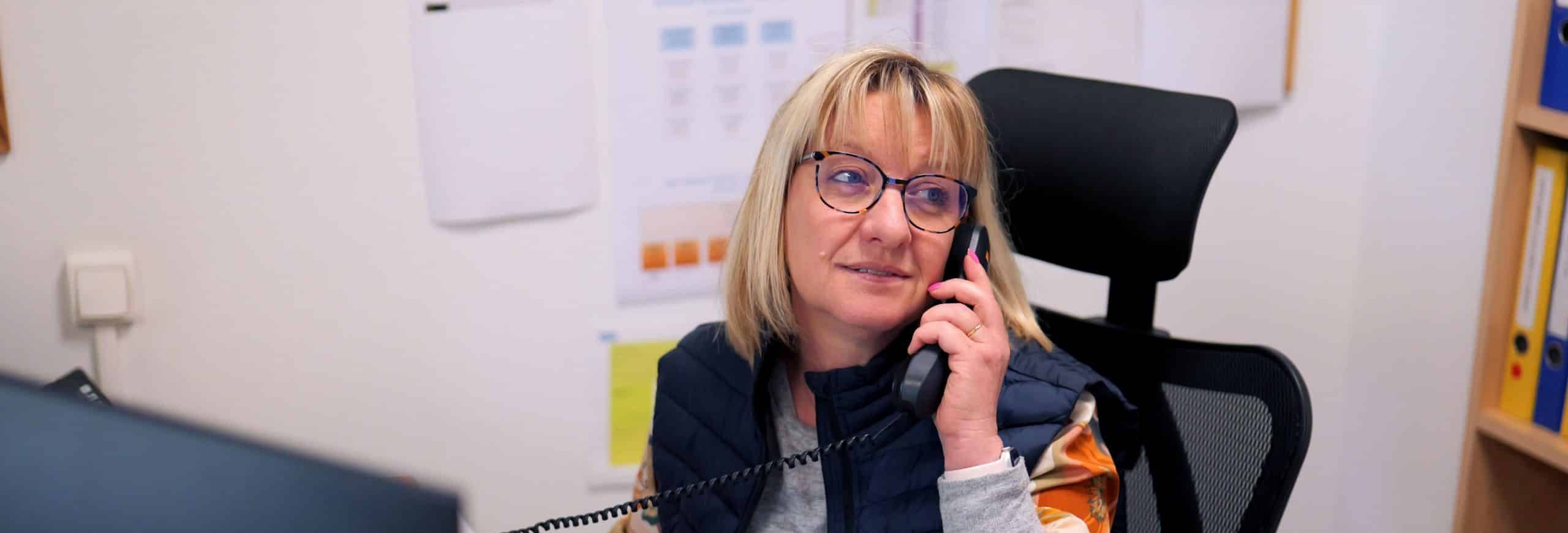 Secrétaire souriant au téléphone à son bureau