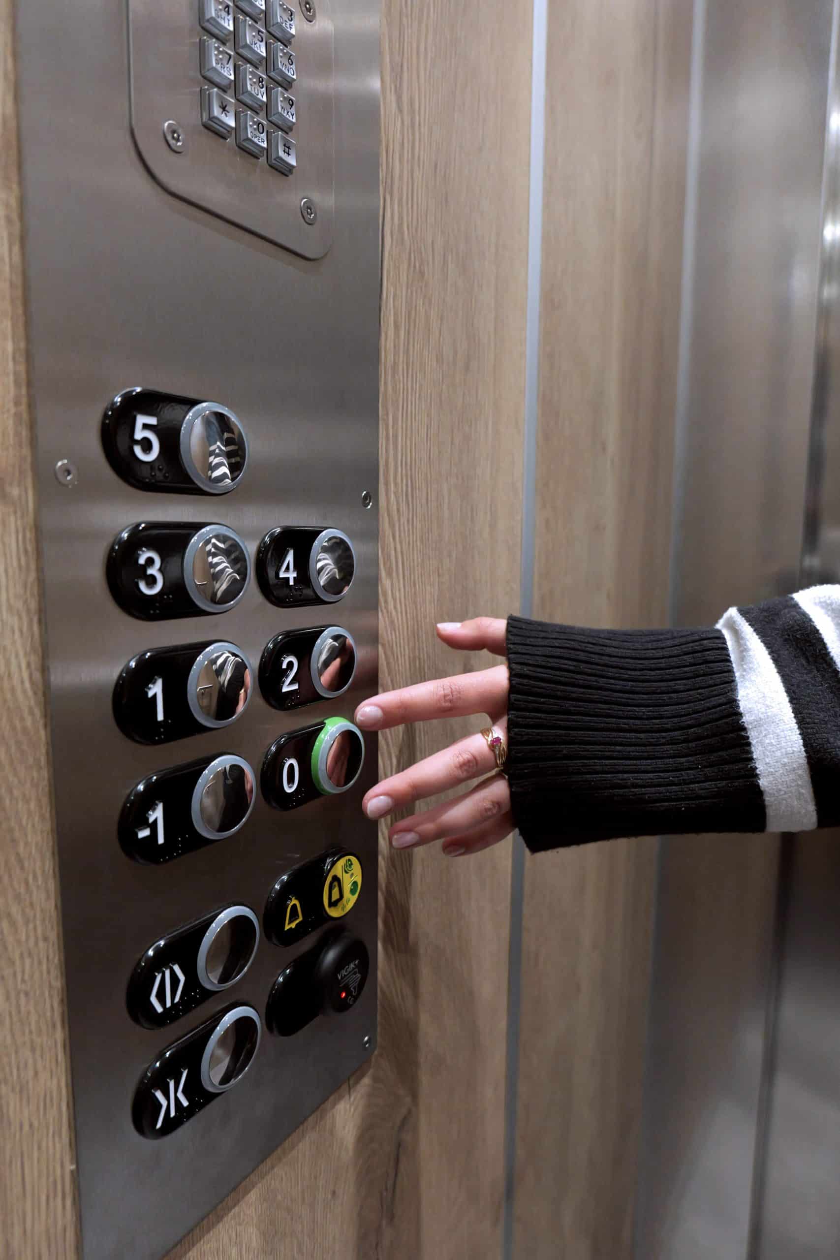 Main d'un habitant cliquant sur un bouton dans l'ascenseur